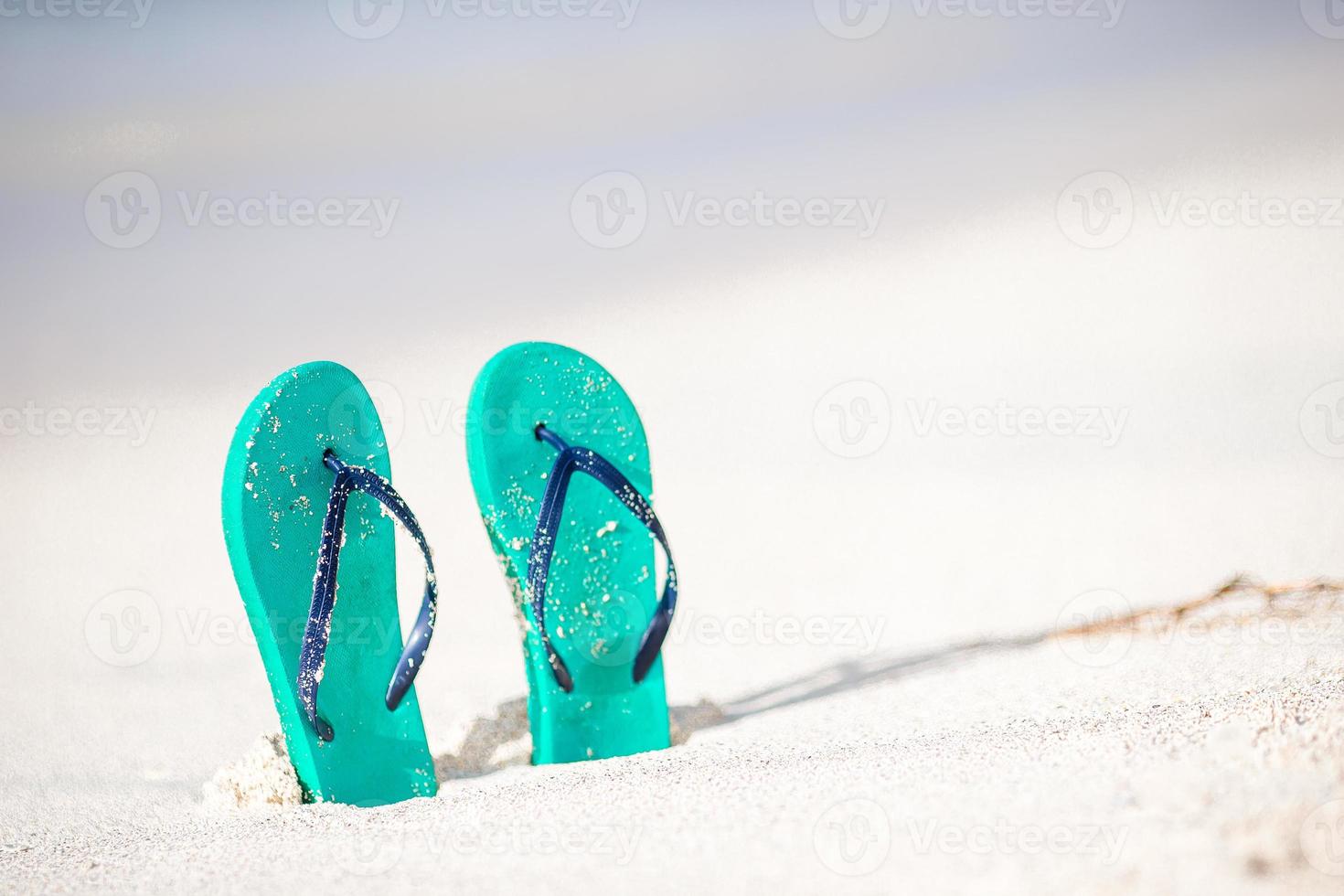 Summer mint flip flops with sunglasses on white beach photo