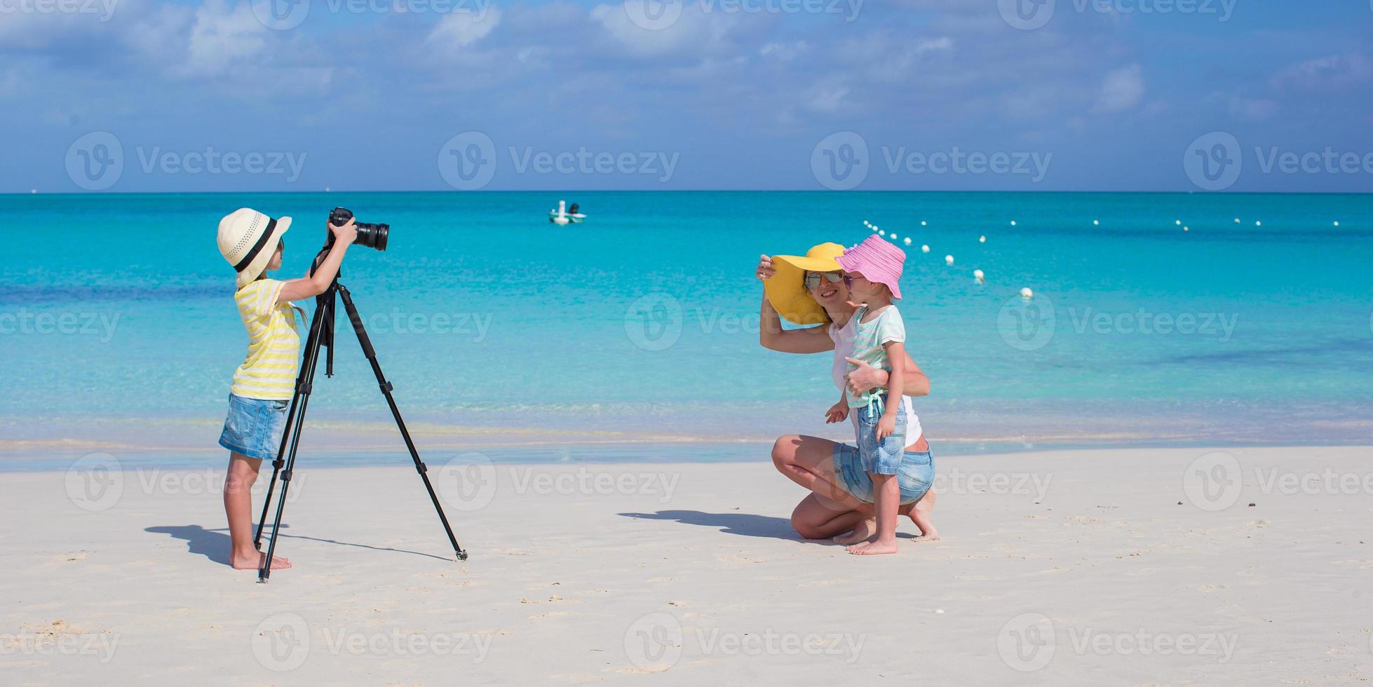 Little girl making photo of her mom and sister at the beach