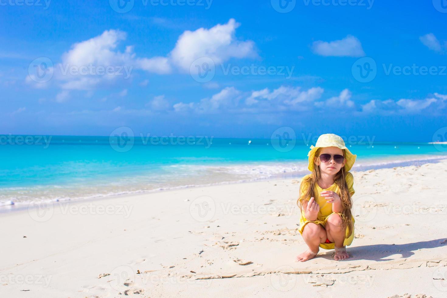 Happy little girl in hat on beach during summer vacation photo