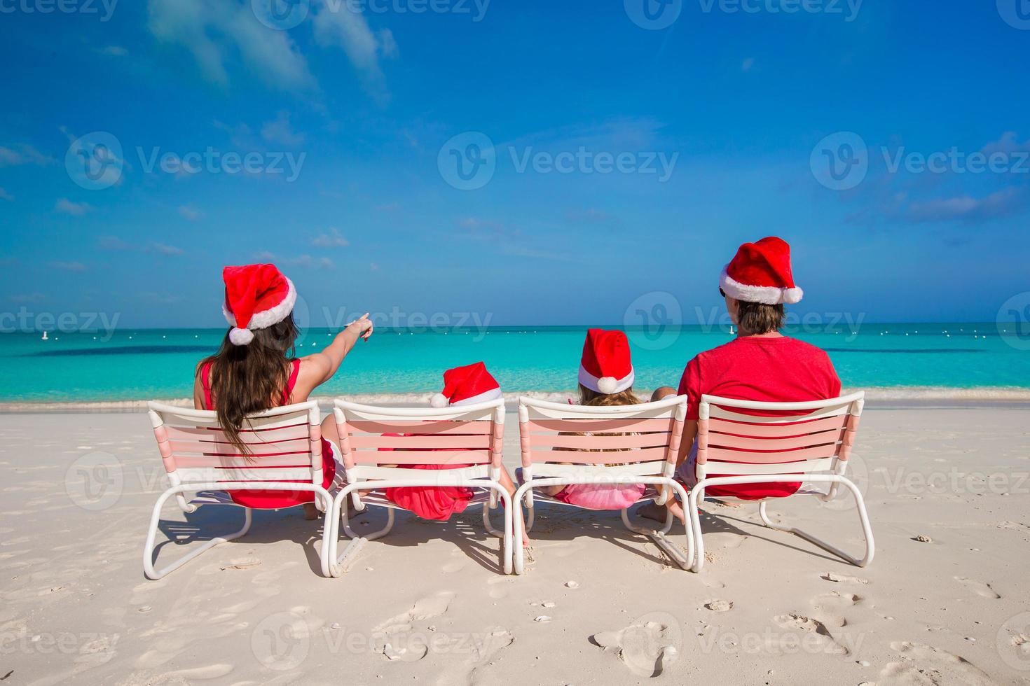 Happy family of four on beach in red Santa hats photo