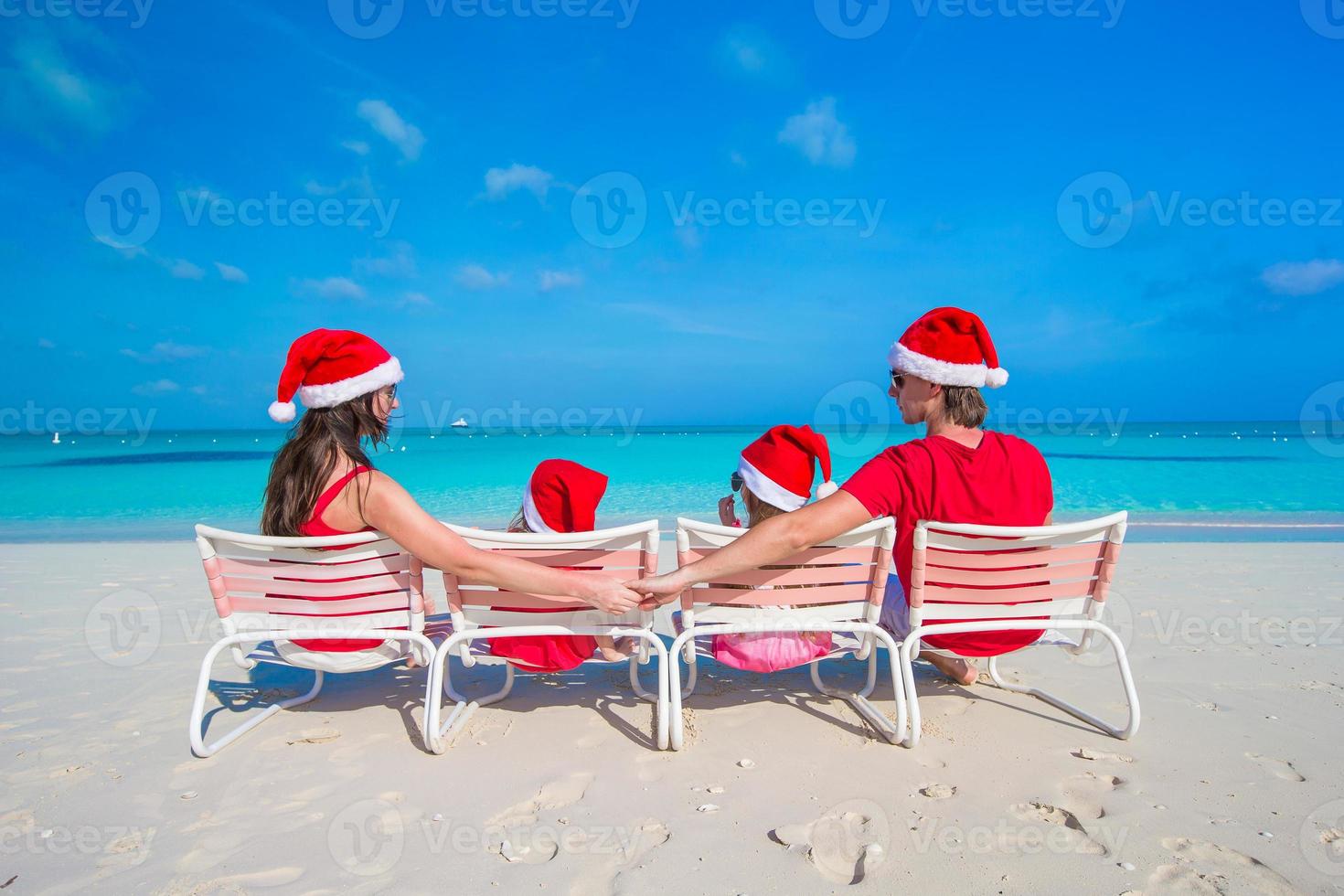 Family in santa hats having fun on tropical beach photo