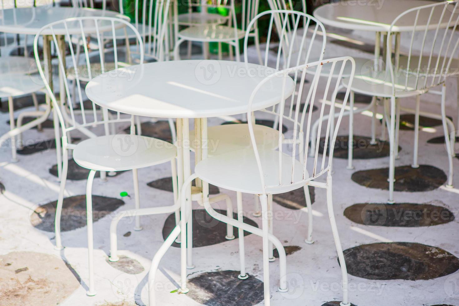 White tables with chairs at summer empty open air cafe in Greece photo