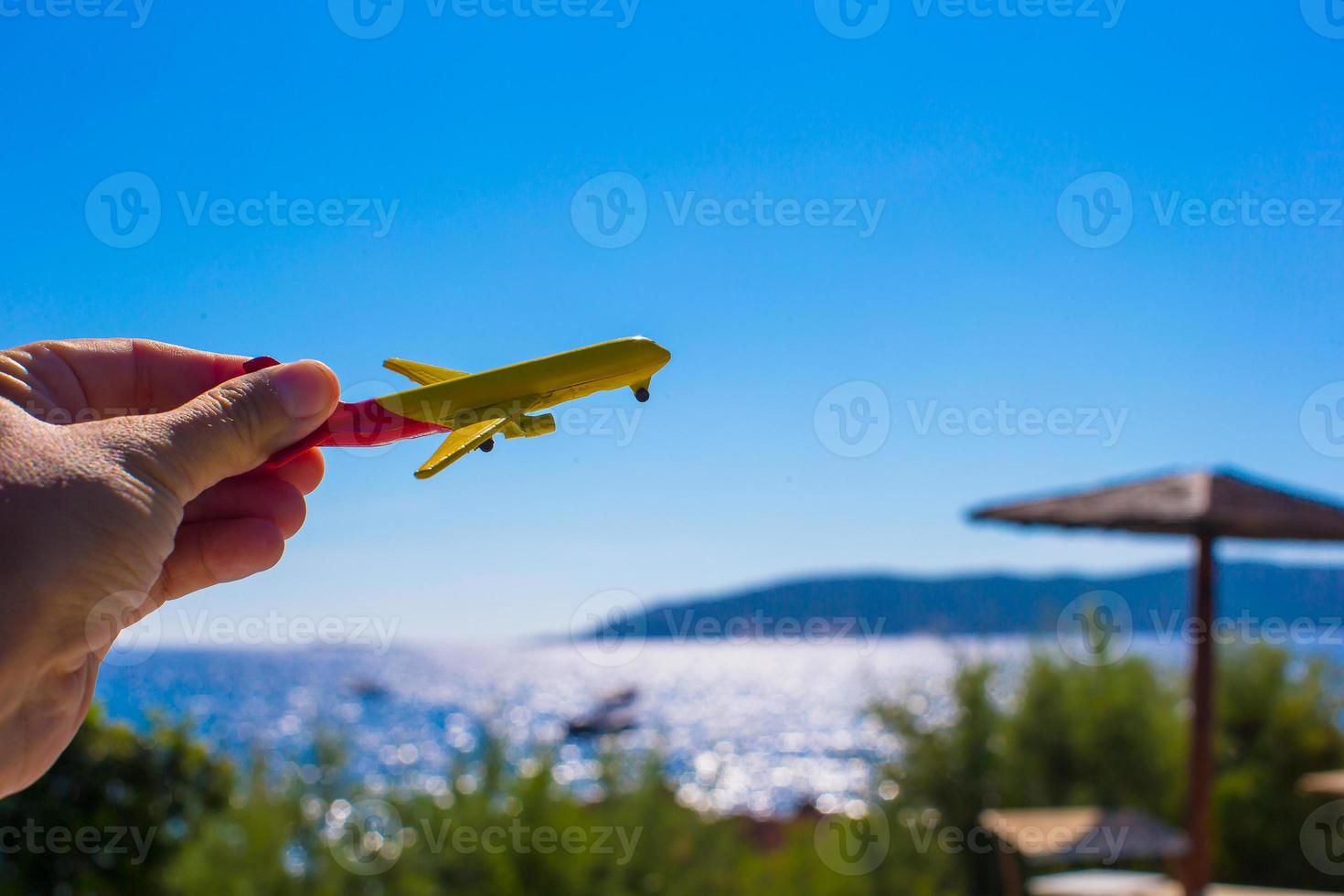 Small plane in female hand on background of blue sky photo