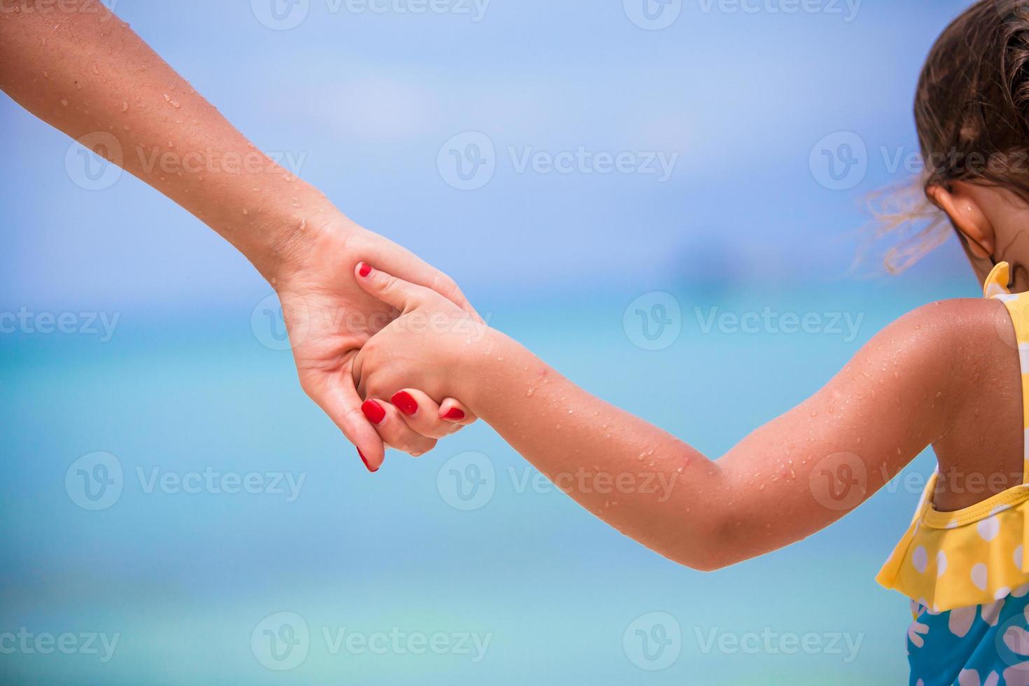 Trust family hands of child girl and mother on white beach photo