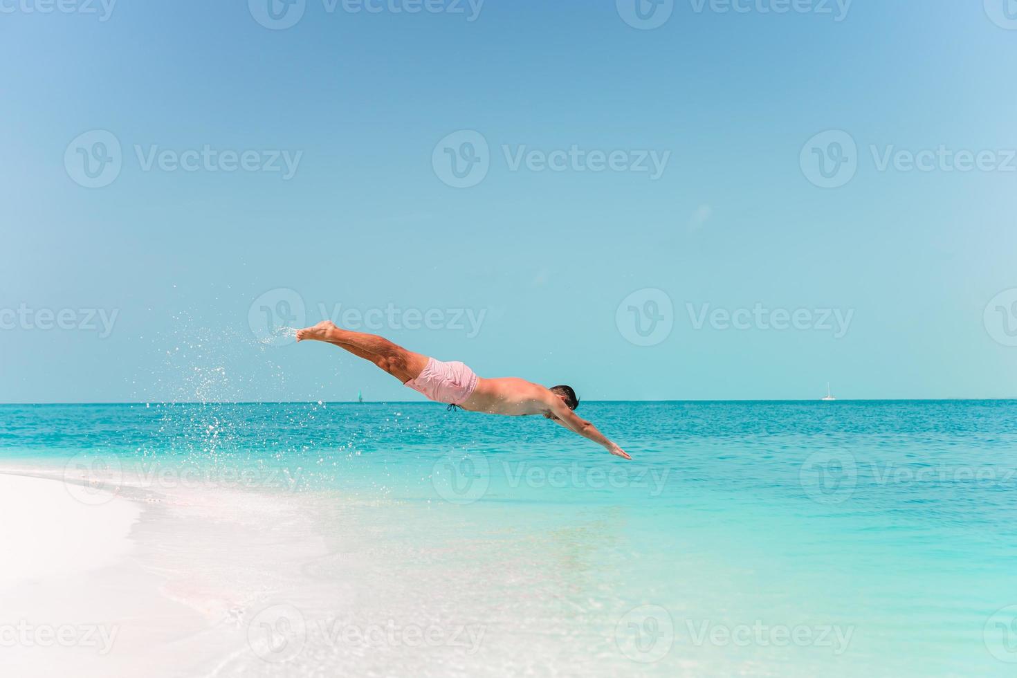 Young man plunging into the turquoise sea photo