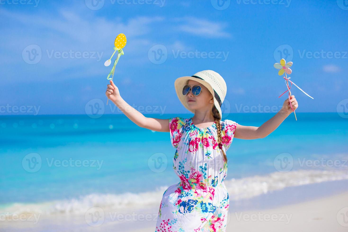 Happy little girl in hat on beach during summer vacation photo
