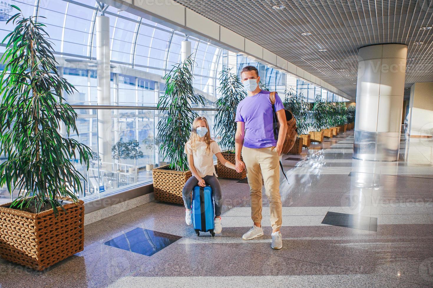 Dad and little girl with medical masks at airport. Protection against Coronavirus and gripp photo