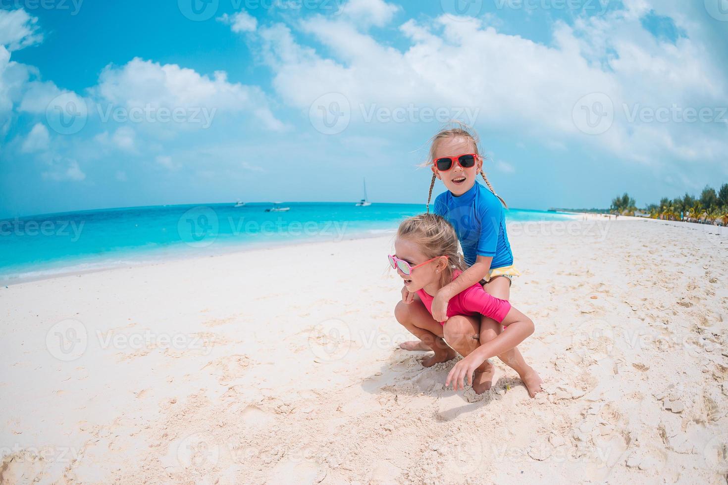 Little happy funny girls have a lot of fun at tropical beach playing together photo