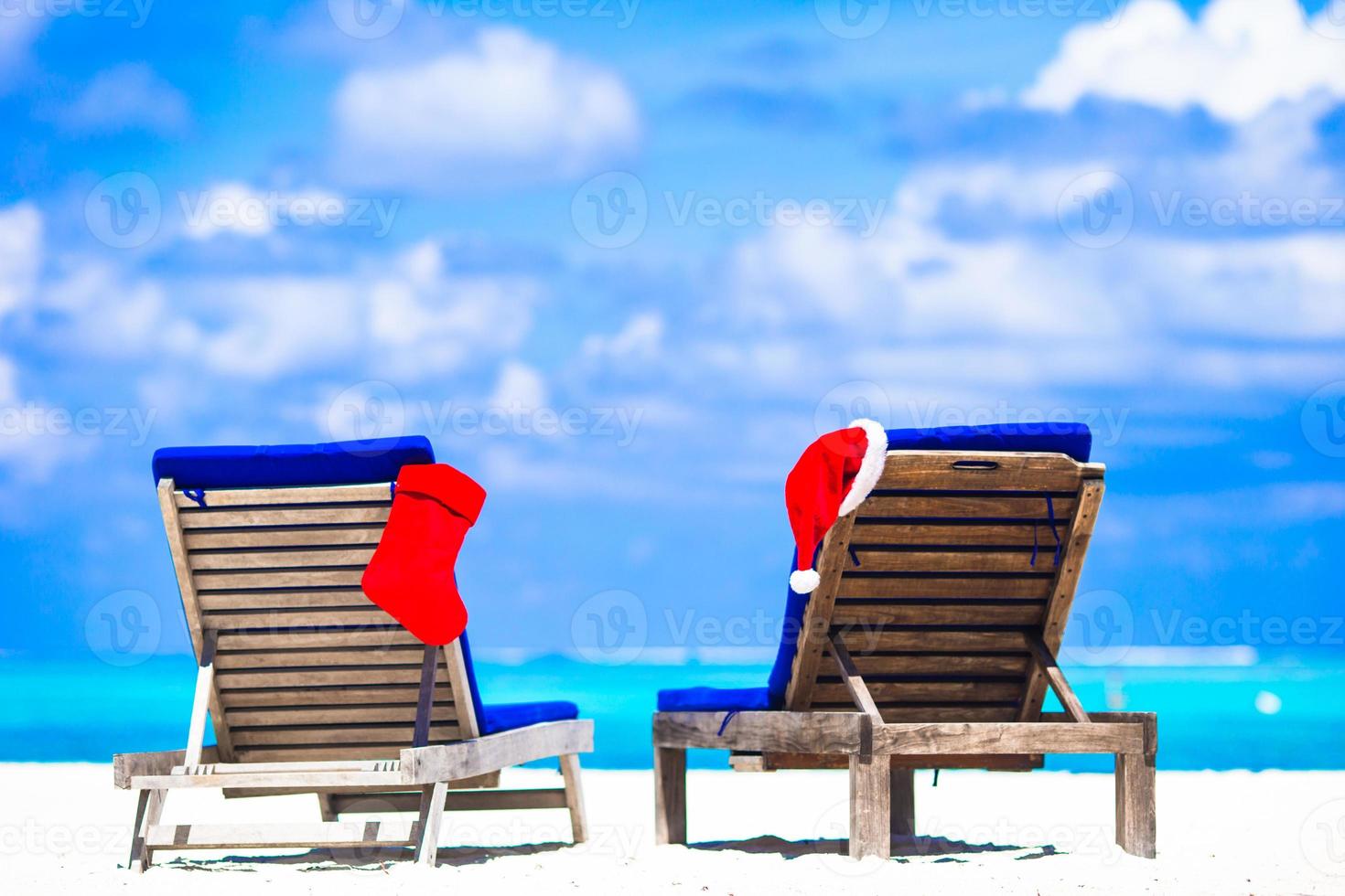 Red Christmas stocking and Santa Hat on chair at tropical white beach photo