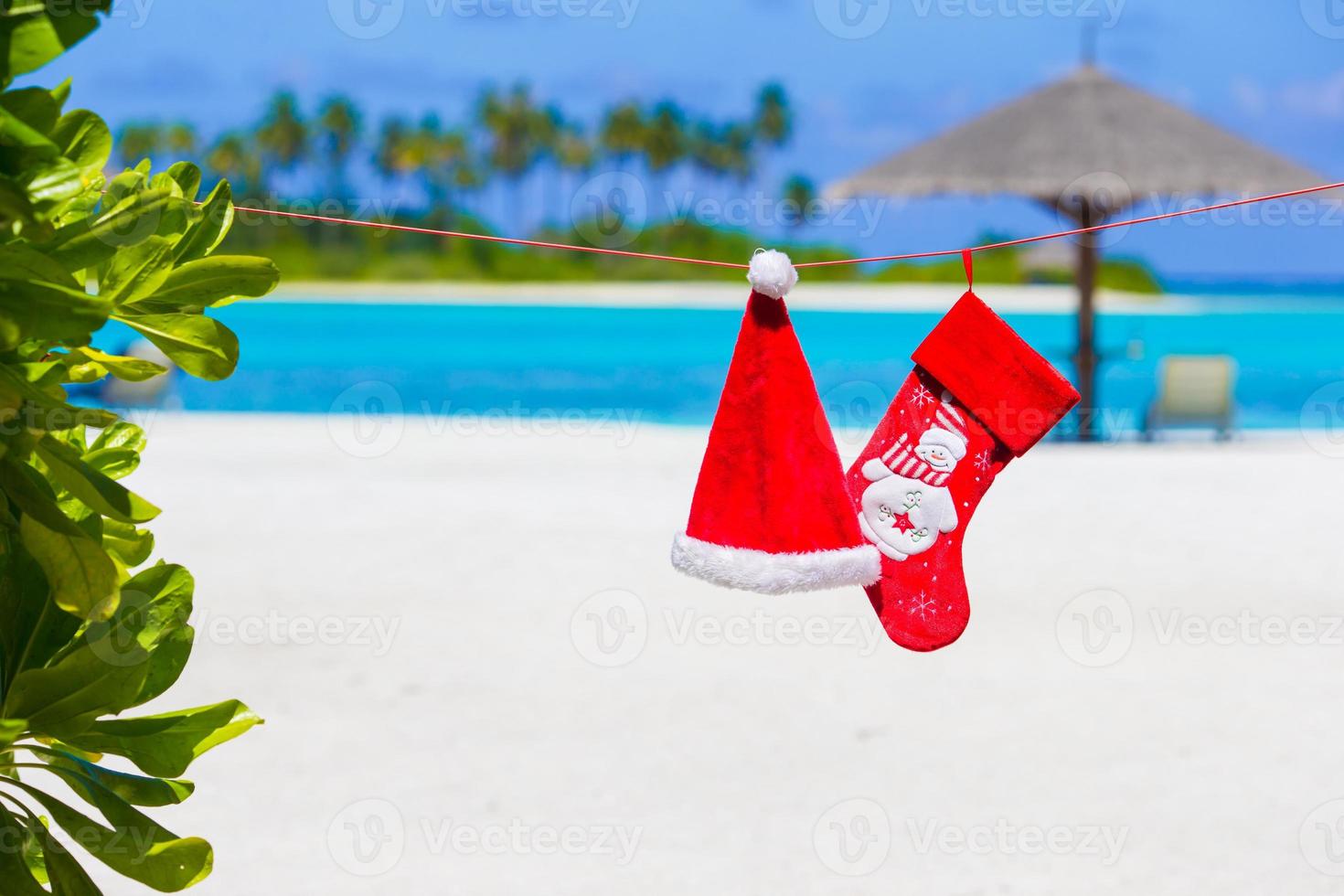 Red Santa hat and Christmas stocking on the beach photo