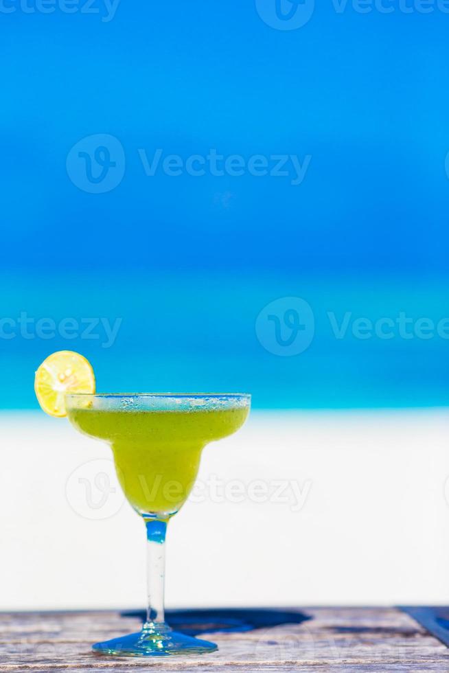 Green tasty cocktail on tropical white beach photo