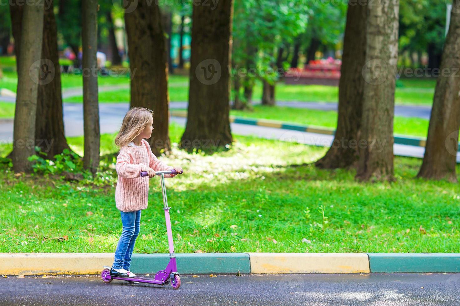 Adorable little girl have fun on the scooter outdoor photo