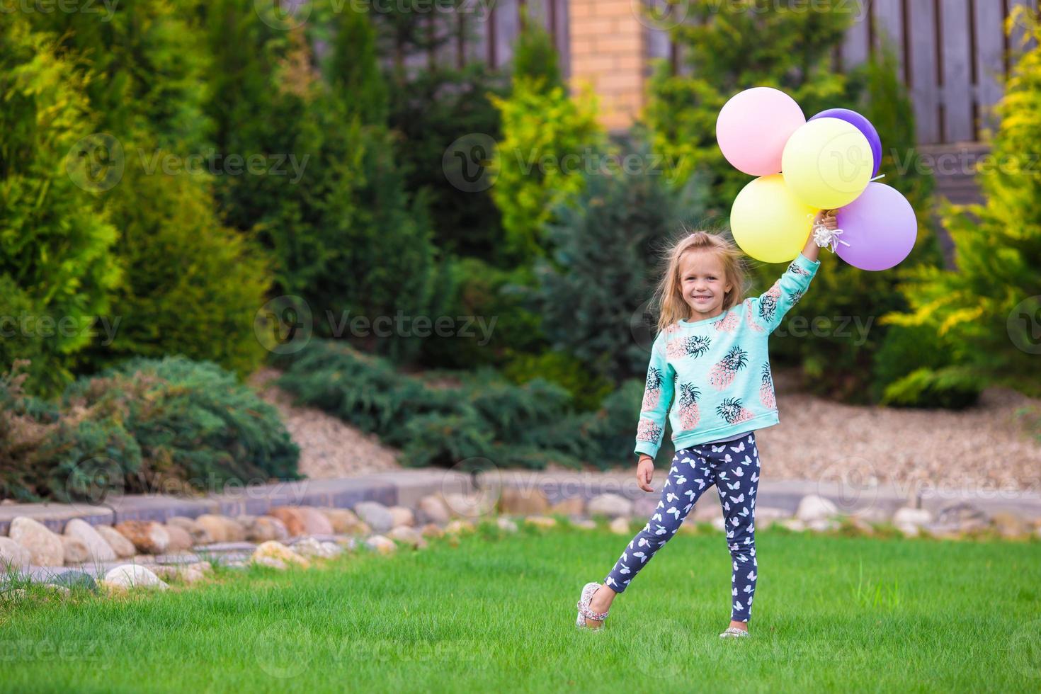 Happy little girl playing with balloons outdoors photo