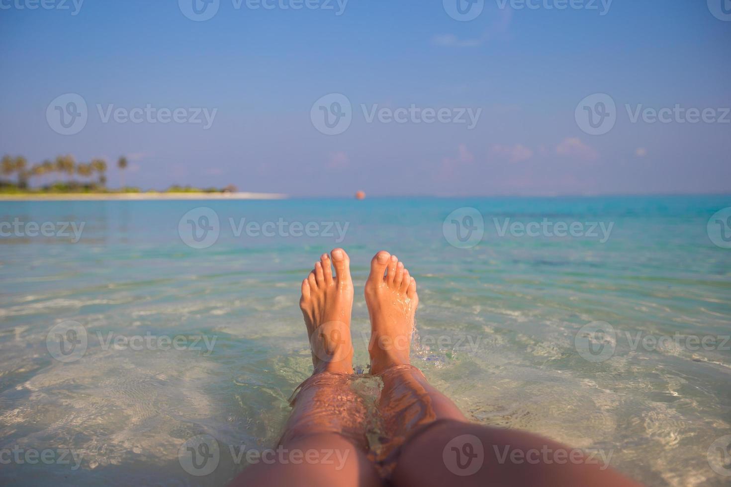 Female feet on white sandy beach and clear water photo