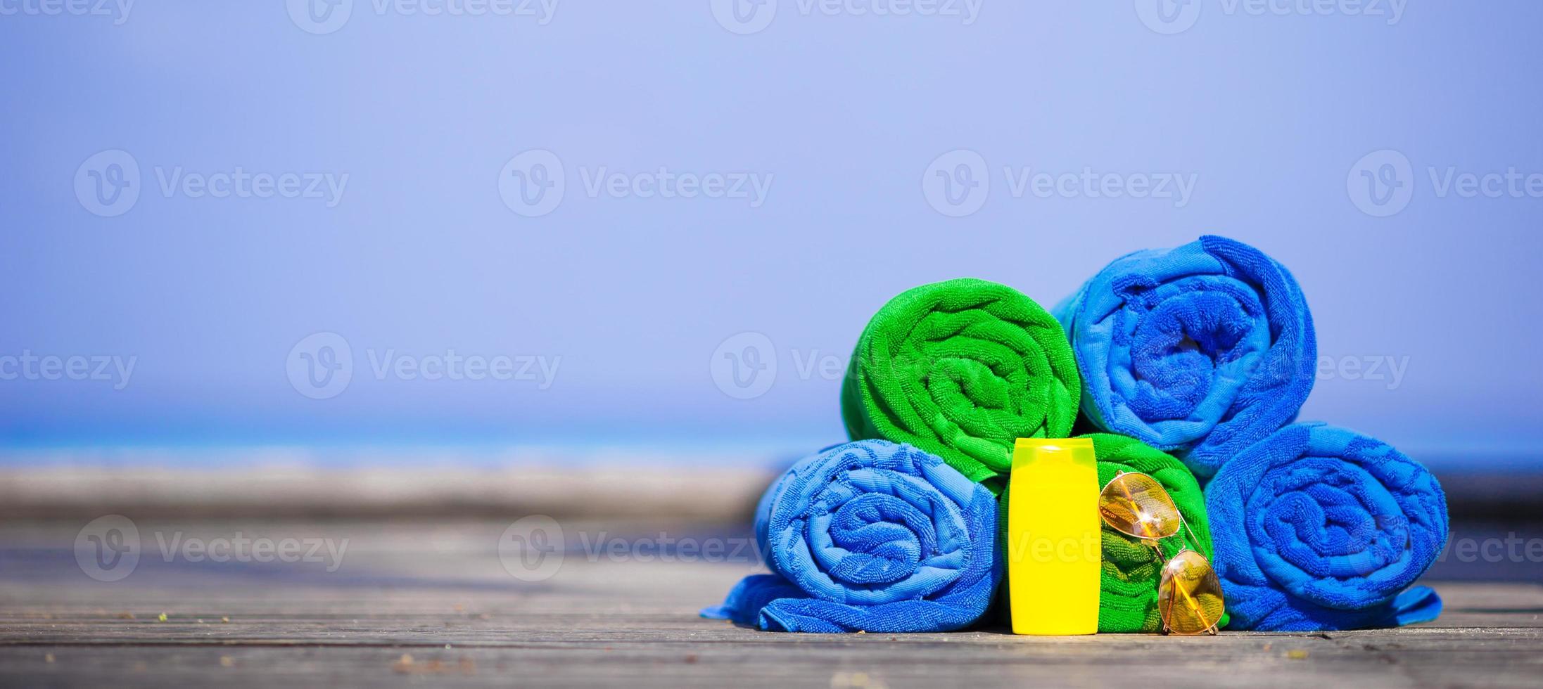 Beach and summer vacation accessories concept - close-up of colorful towels, swimming goggles and sunblock photo