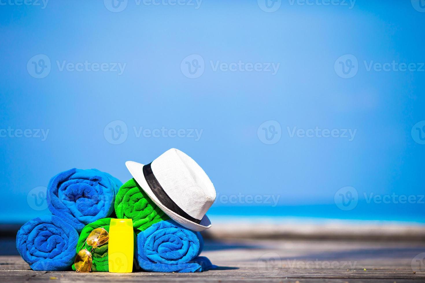 Beach and summer vacation accessories concept - close-up of colorful towels, hat, swimming goggles and sunblock photo