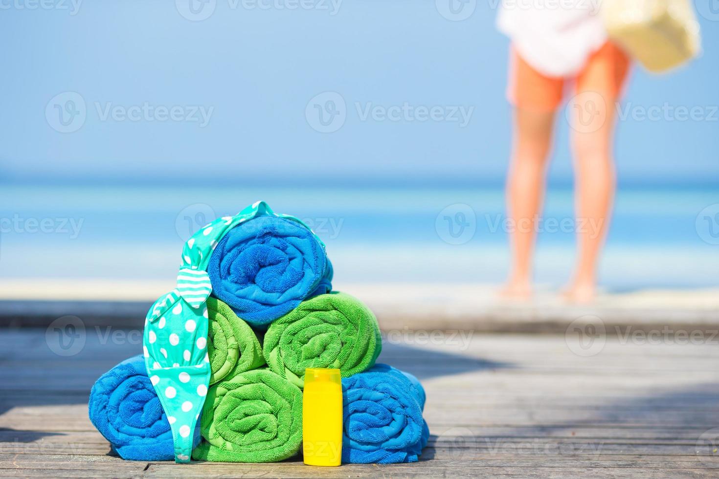 Beach and summer accessories concept - colorful towels, swimsuit and sunsblock background beautiful woman photo