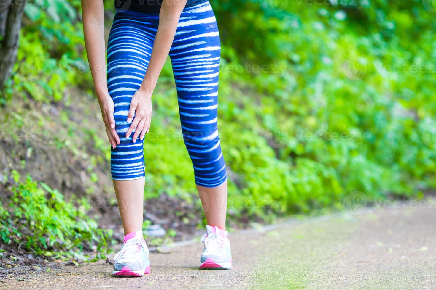 Female athlete suffering from pain in leg while exercising outdoors photo