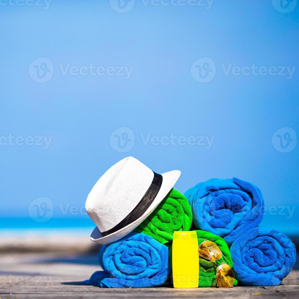 Beach and summer vacation accessories concept - close-up of colorful towels, hat, swimming goggles and sunblock photo