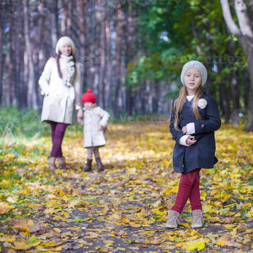 Little cute girls and young mother in autumn park have fun photo