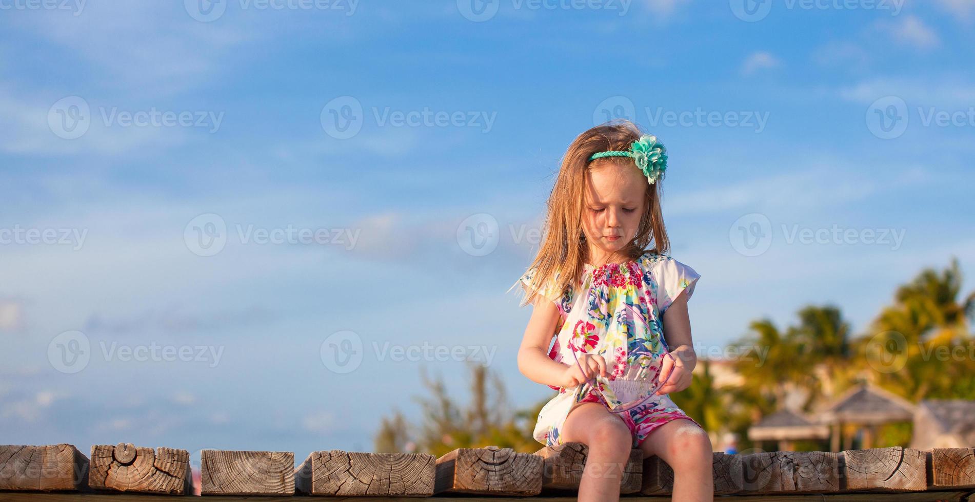 Adorable little girl at white tropical beach in sunset photo