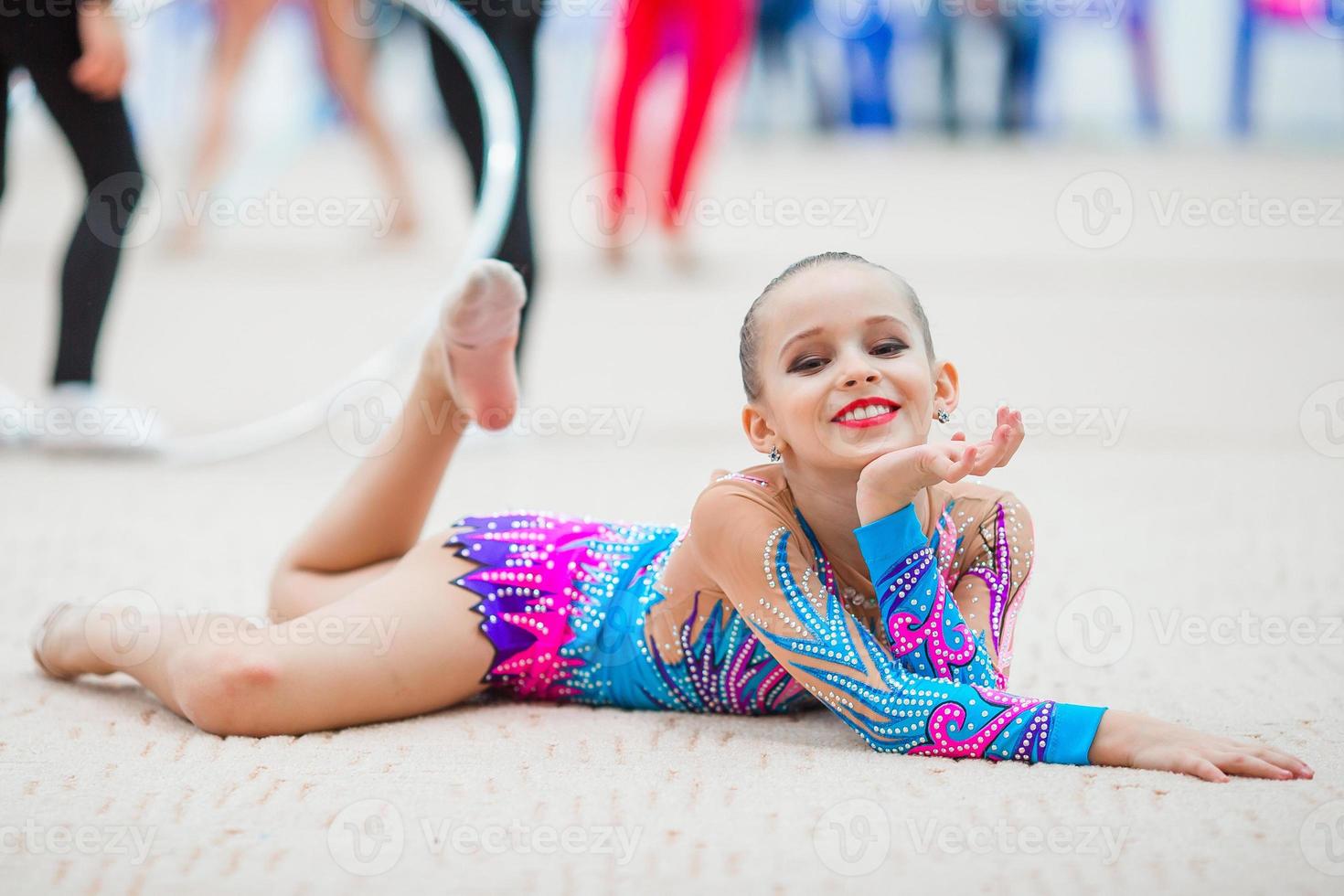 hermosa pequeña gimnasta entrenando en la alfombra y lista para las competiciones foto