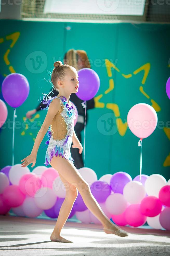 Adorable gymnast participates in competitions in rhythmic gymnastics photo