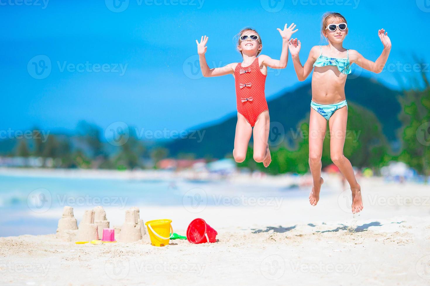 Two kids making sand castle and having fun at tropical beach photo