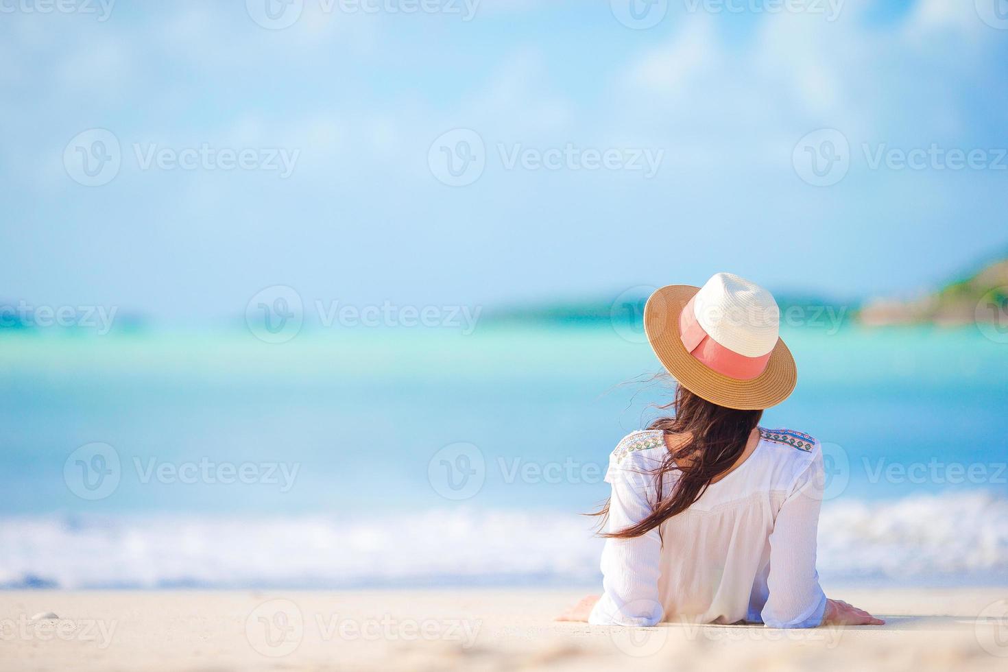 Young woman enjoying the sun sunbathing by perfect turquoise ocean. photo