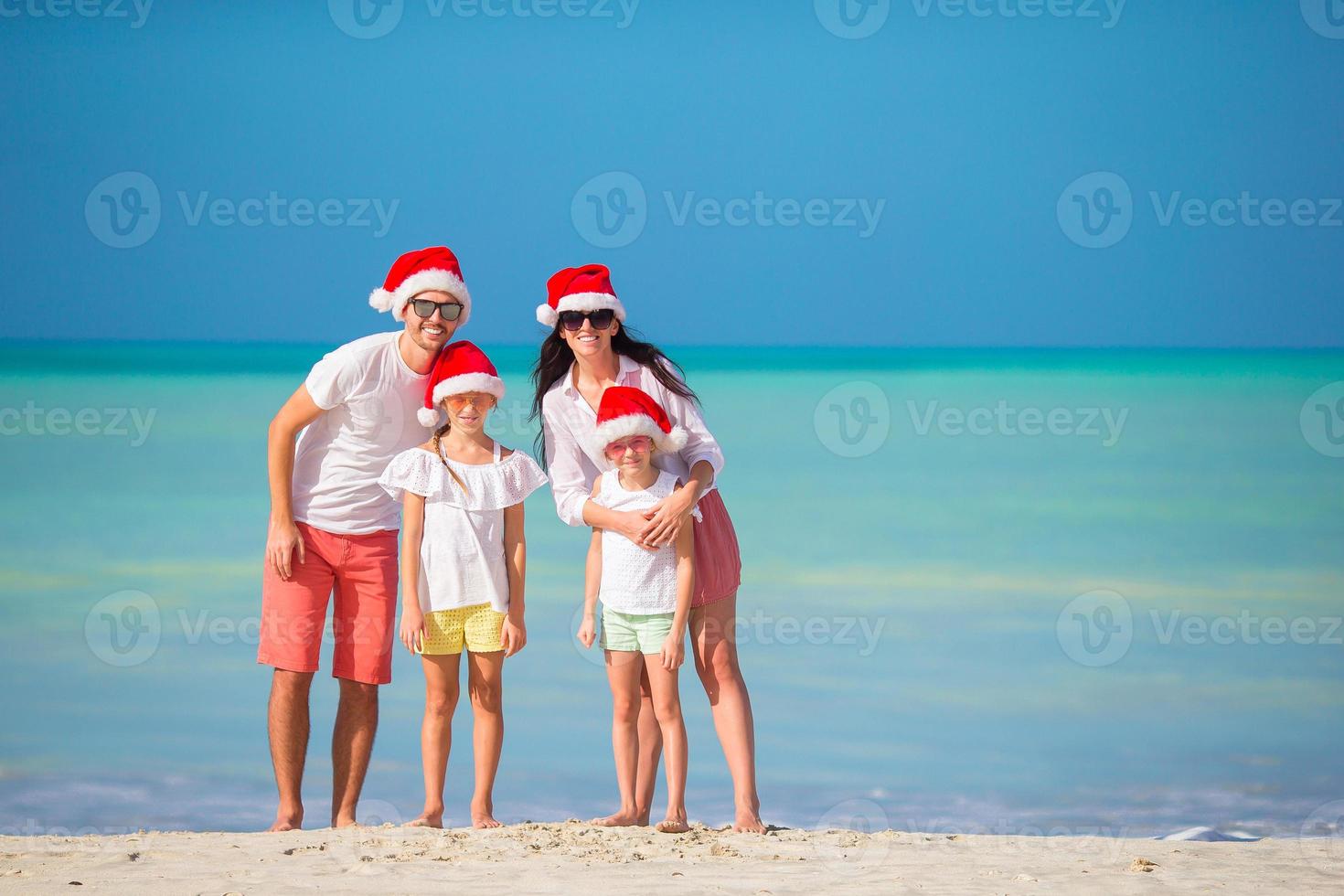 Happy family with two kids in Santa Hat on summer vacation photo