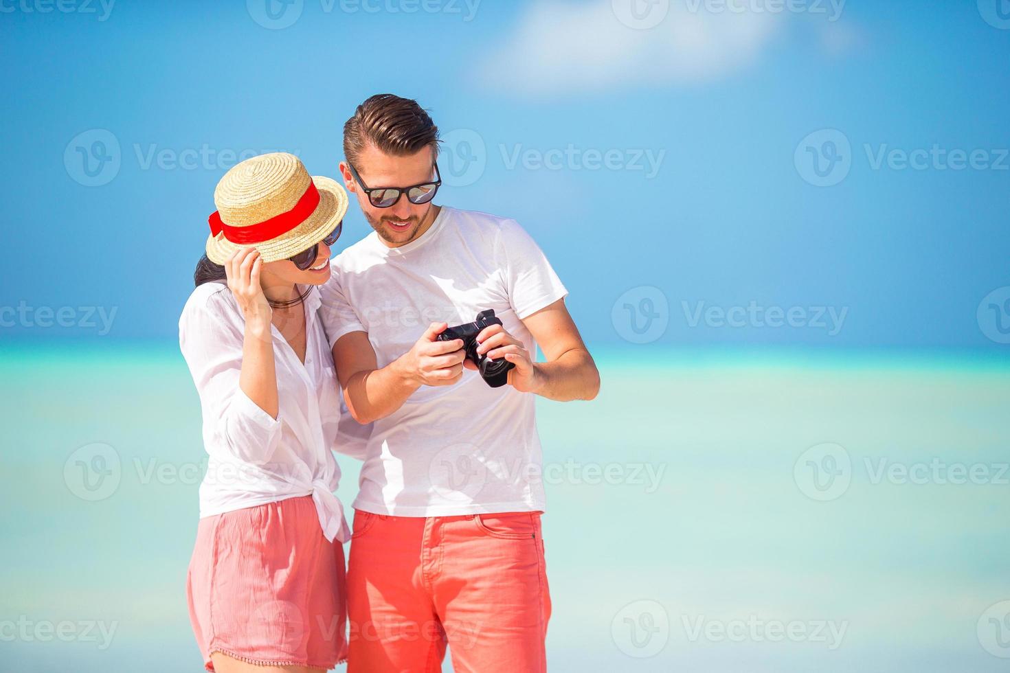 Happy couple taking a photo on white beach on honeymoon holiday
