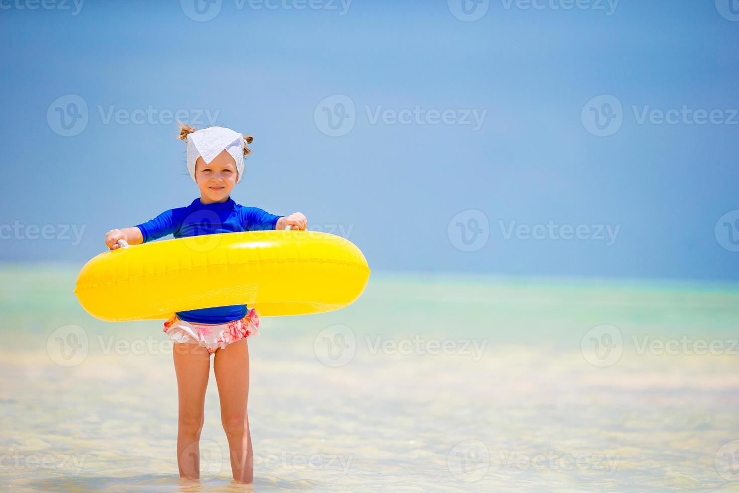 Happy kid with inflatable rubber circle having fun on the beach photo