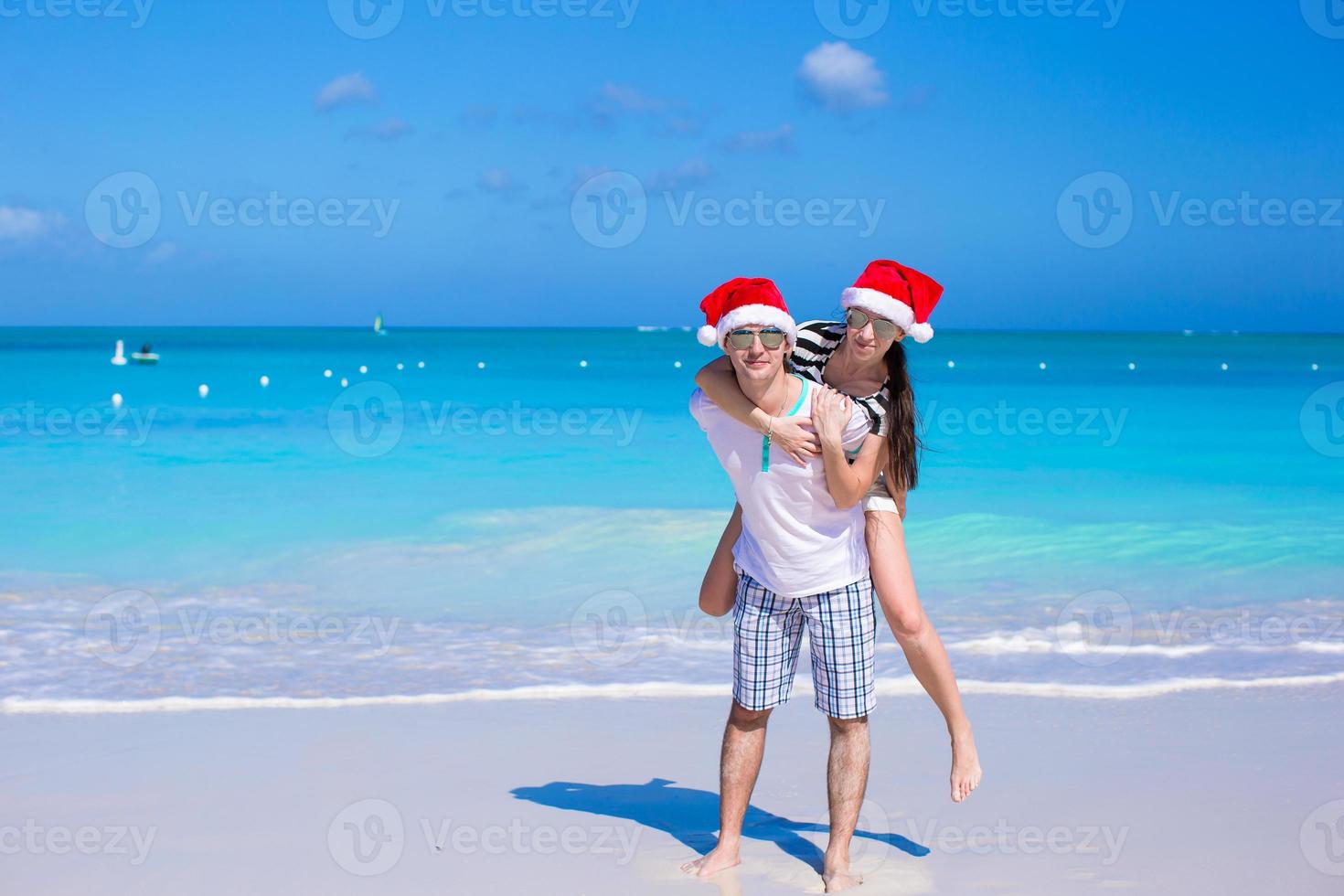 Back view of couple in Santa hats enjoy beach vacation photo