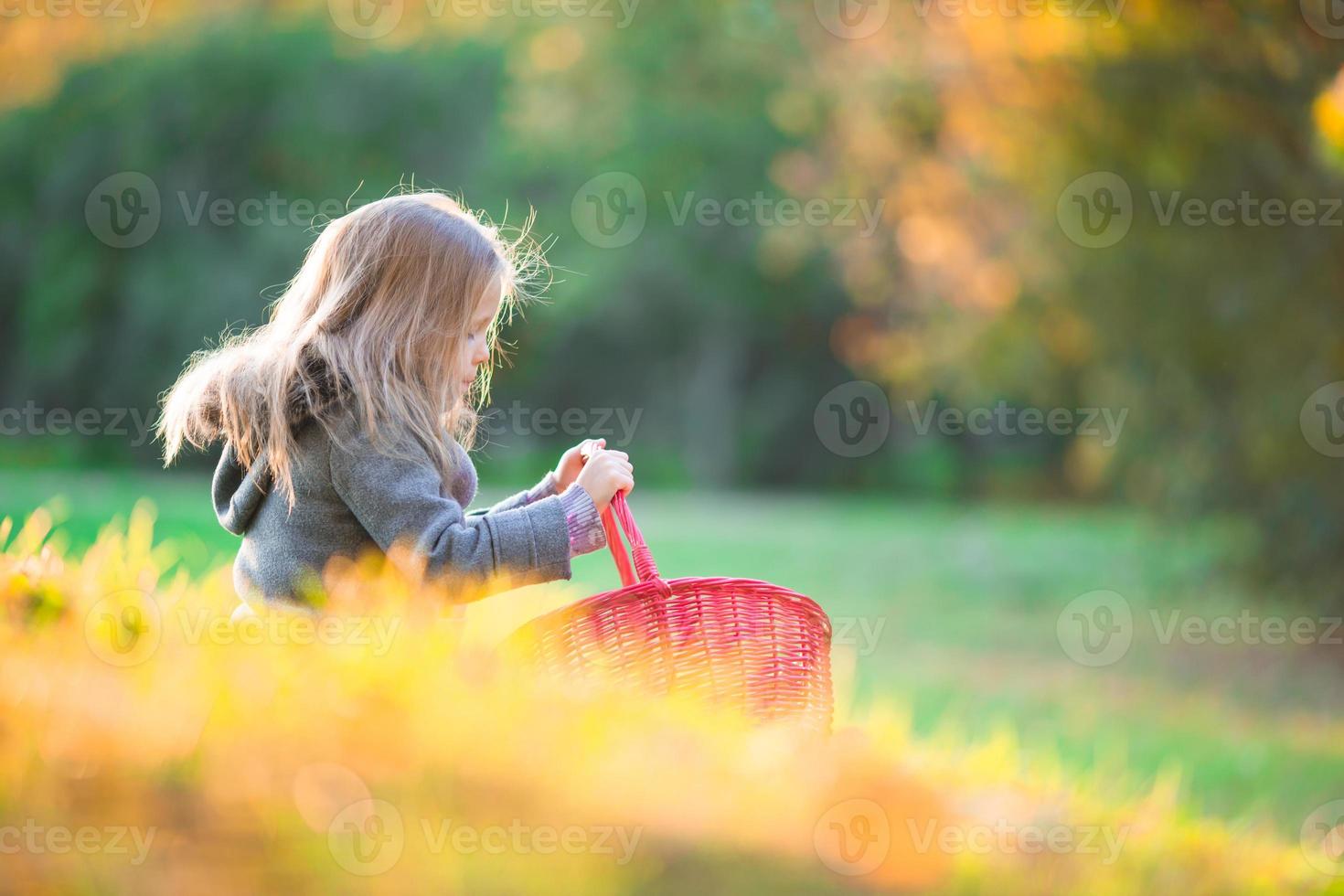 adorable niña con una canasta en el frío día de otoño al aire libre foto