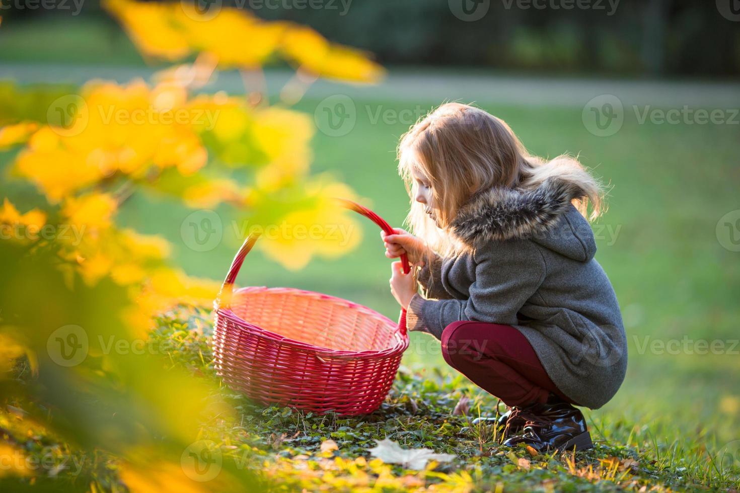 adorable niña con una canasta en el frío día de otoño al aire libre foto