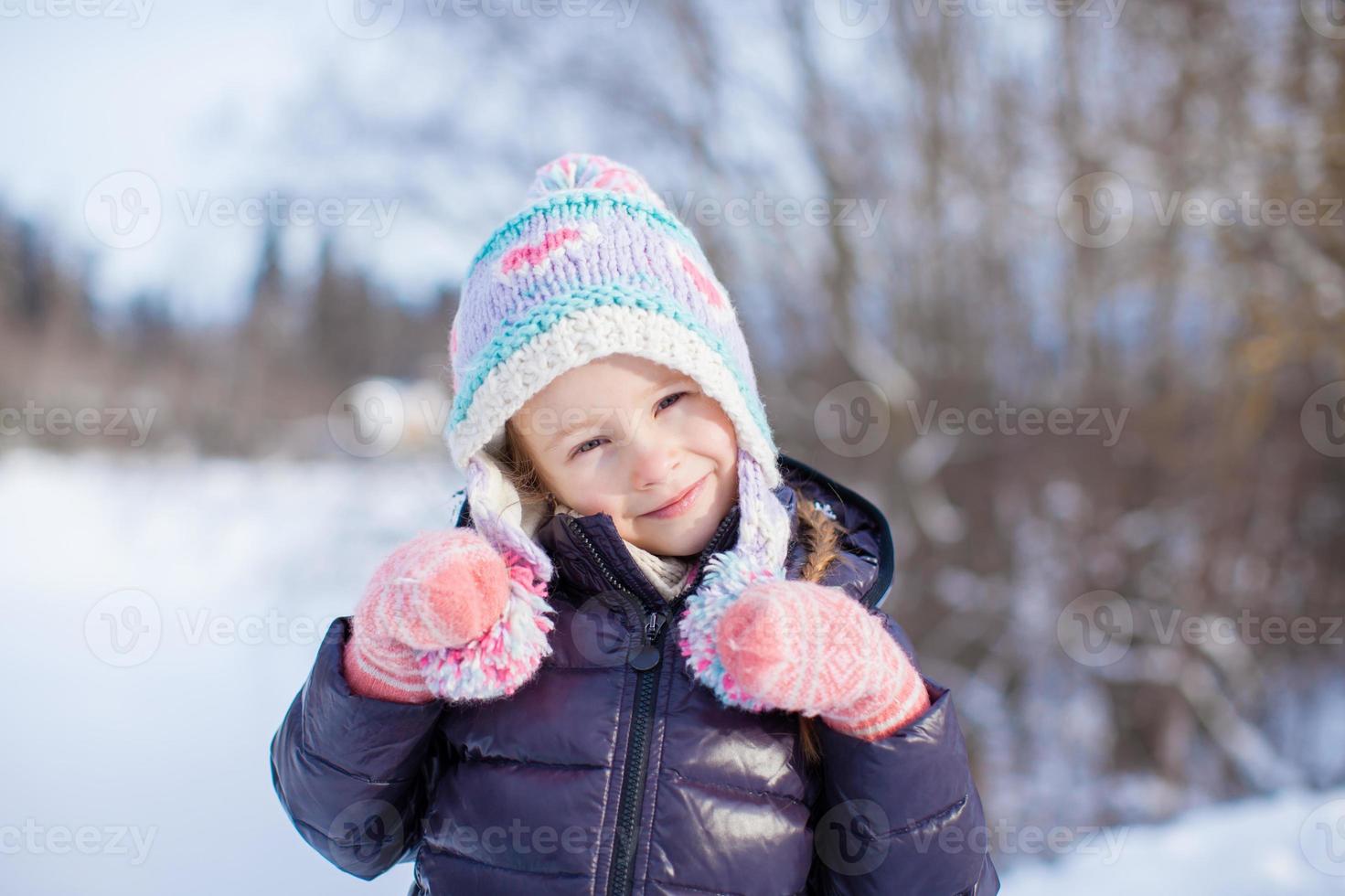 Portrait of little adorable girl in snow sunny winter day photo