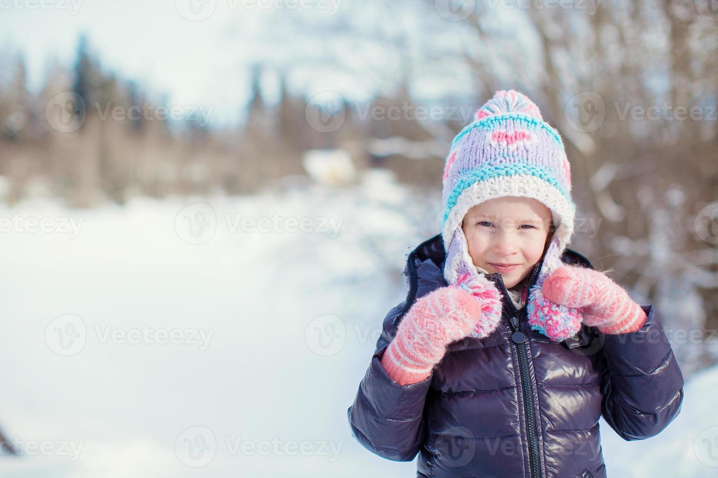 Portrait of little adorable girl in snow sunny winter day photo