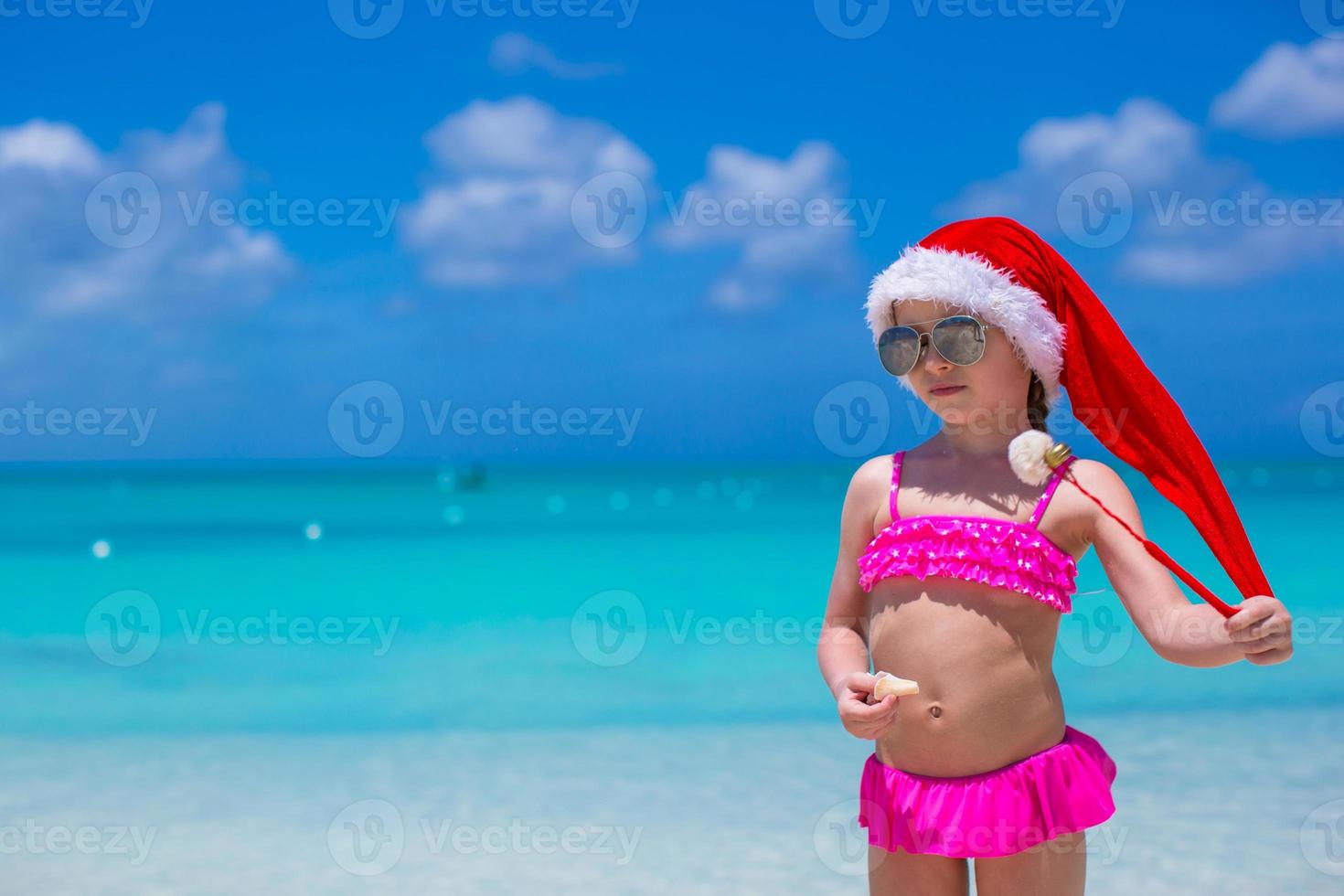 Little adorable girl in red Santa Hat enjoy beach vacation photo