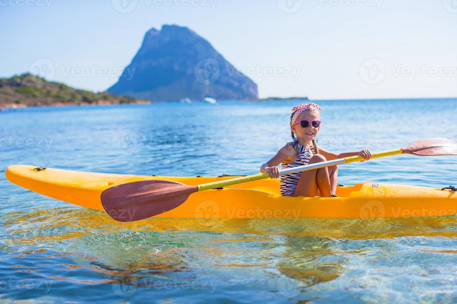 pequeña niña valiente y linda haciendo kayak en el mar azul claro foto