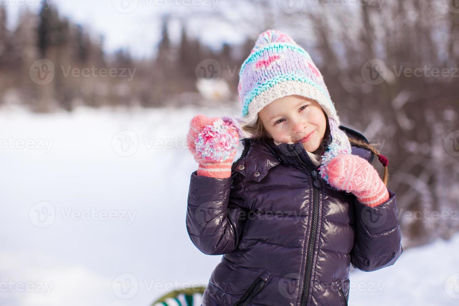 Portrait of little adorable girl in the snow sunny winter day photo