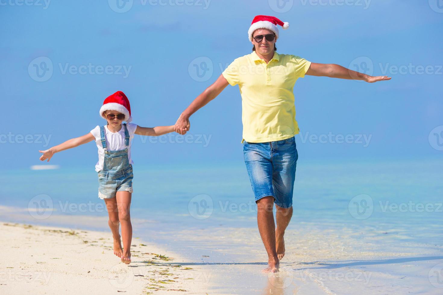 familia feliz con sombreros de santa durante las vacaciones de navidad en la playa foto