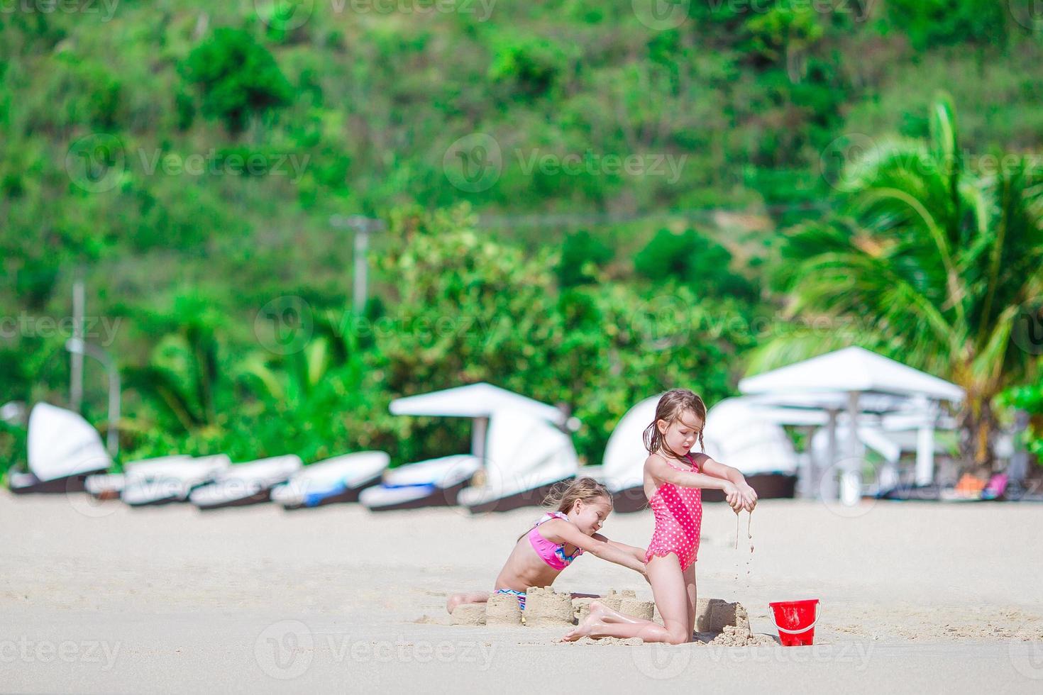 Two kids making sand castle and having fun at tropical beach photo