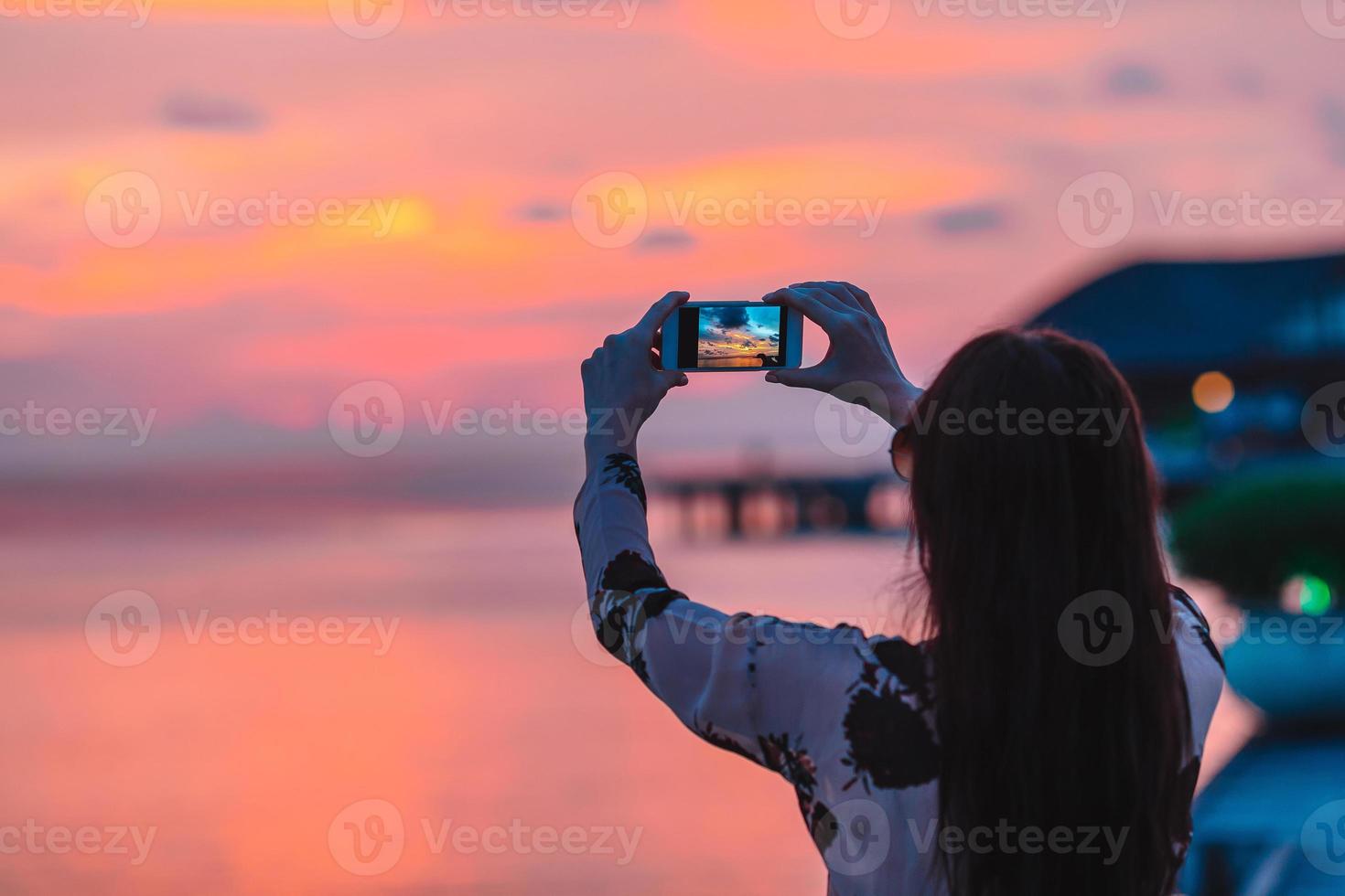 mujer haciendo una foto en su teléfono de una hermosa puesta de sol