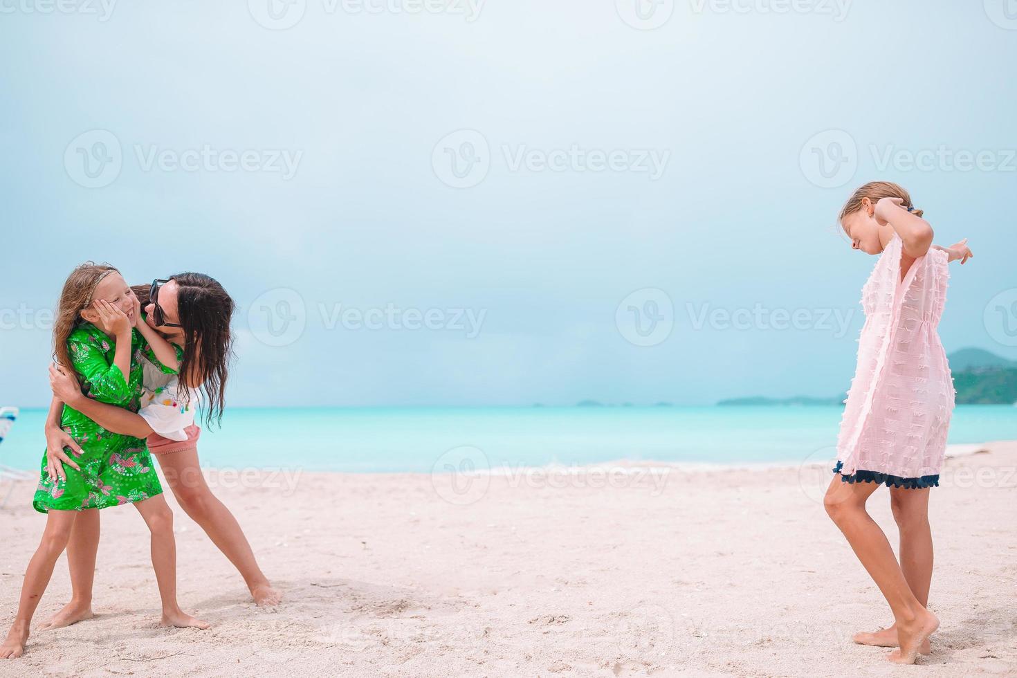 Beautiful mother and her adorable little daughters on the beach photo