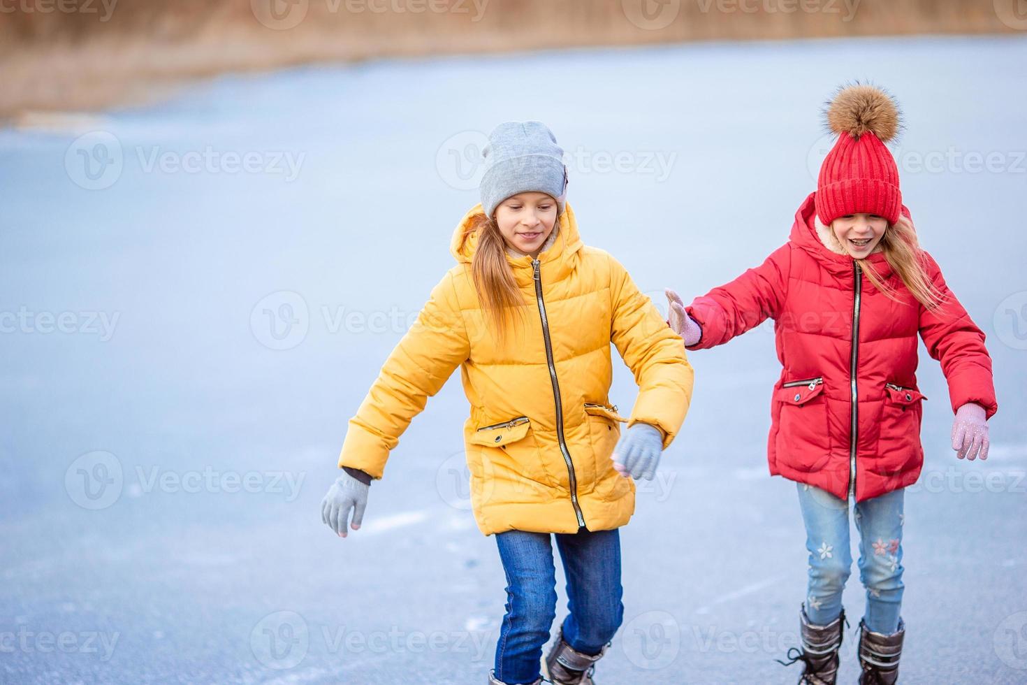 chicas adorables patinando en la pista de hielo al aire libre en el día de nieve de invierno foto