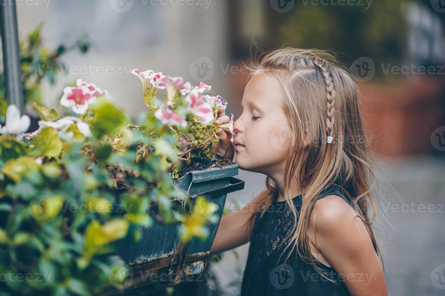 niña adorable sentada cerca de flores de colores en el jardín foto