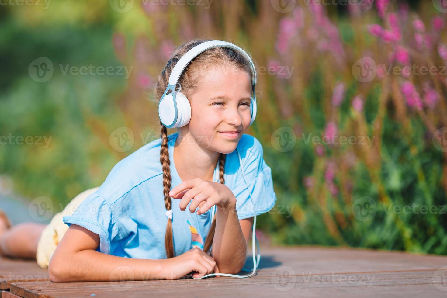 Little adorable girl listening music in the park photo