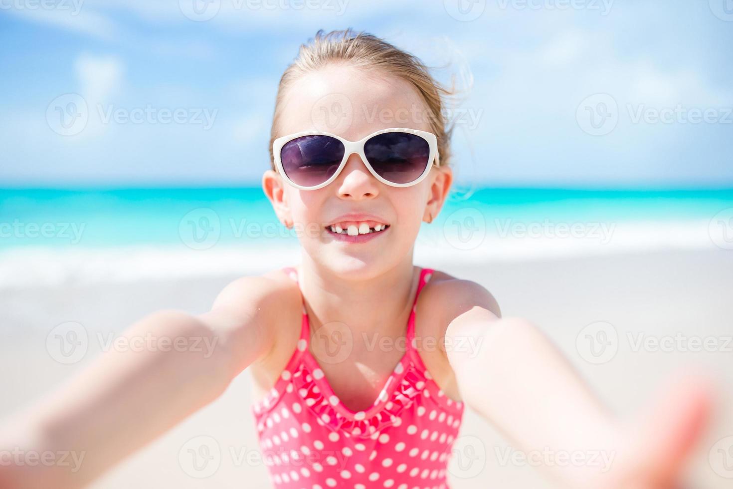 Happy little girl taking selfie at tropical beach on exotic island photo