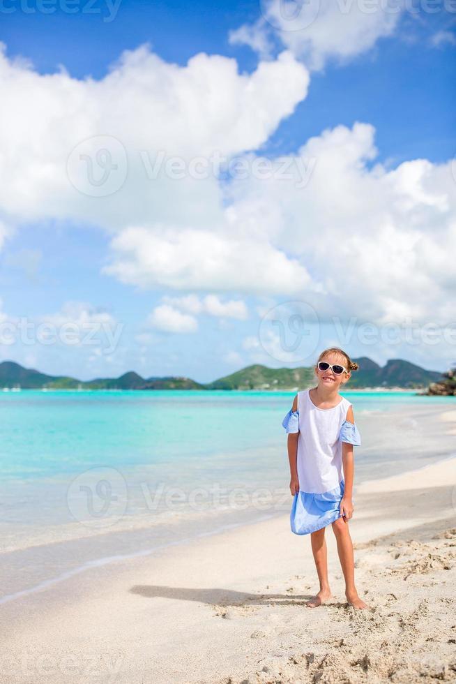 Beautiful little girl in dress at beach having fun. Funny girl enjoy summer vacation. photo