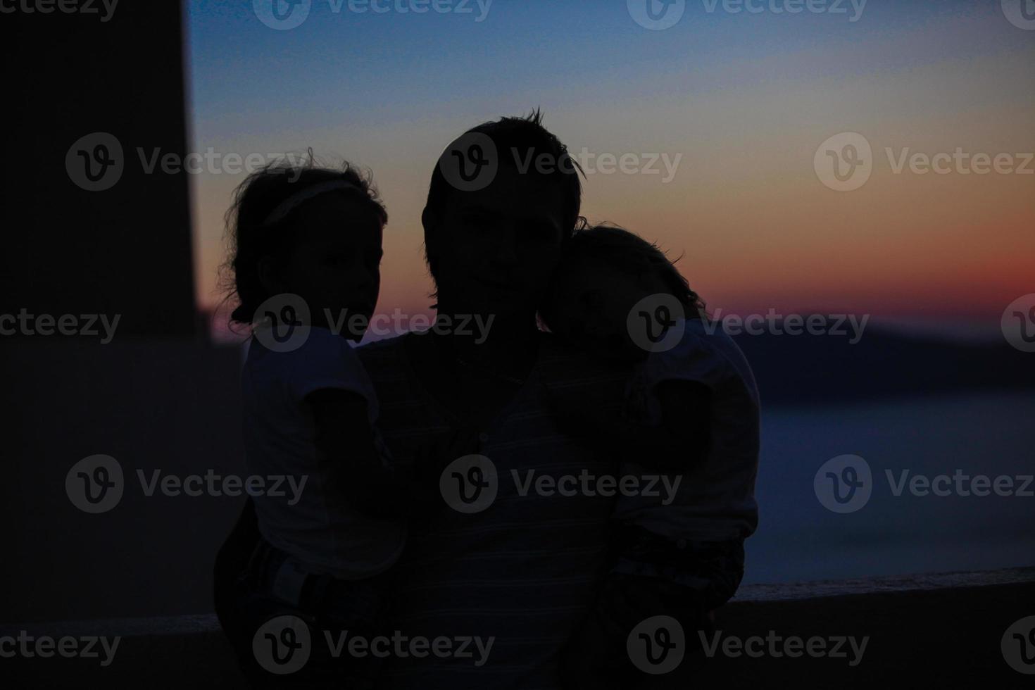 Father and daughter silhouettes in sunset at old greek town photo